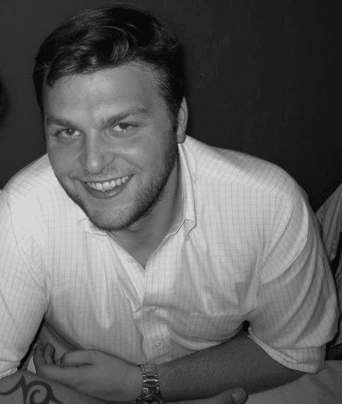 Person wearing a white button-down shirt and wristwatch, sitting at a table.